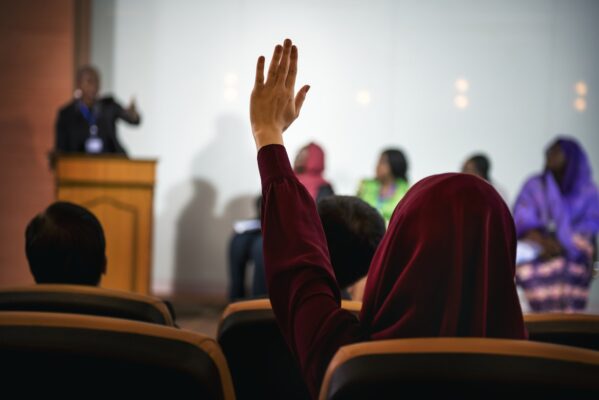 A Person Raising Her Hand to Ask a Question in a Panel Discussion